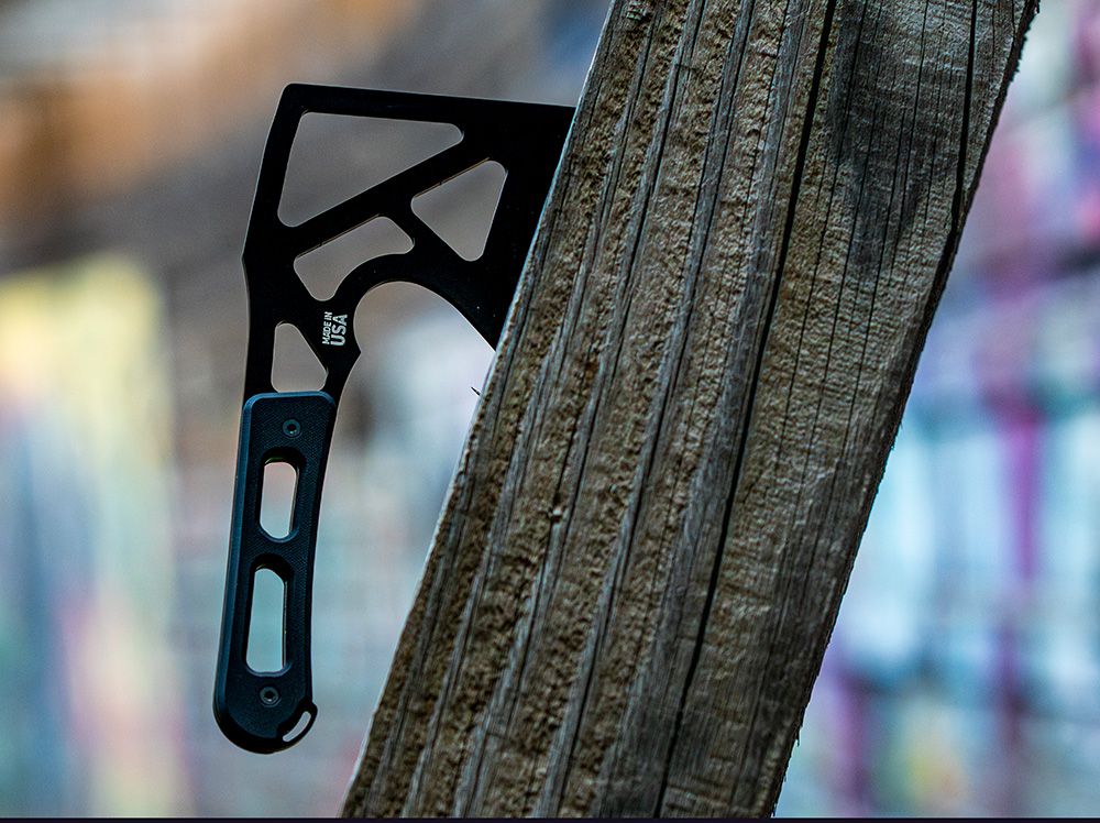 Black HAViK hatchet wedged into a weathered wooden post