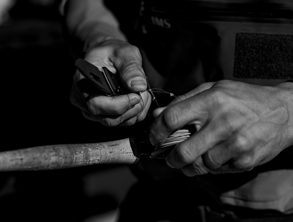 Close-up of hands rigging line onto a cork fly-rod grip