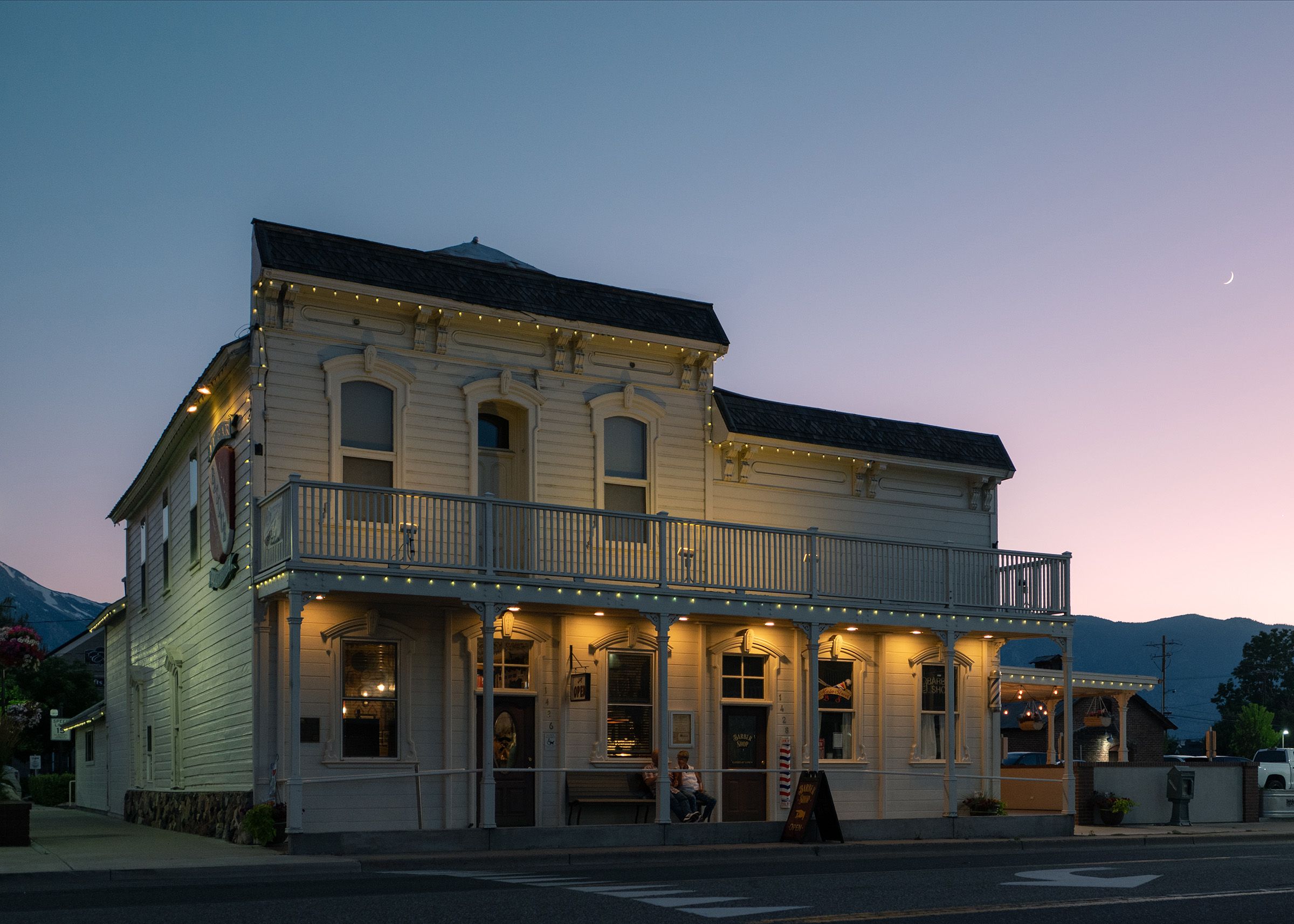 Bar exterior at night with lit windows and sidewalk seating under string lights