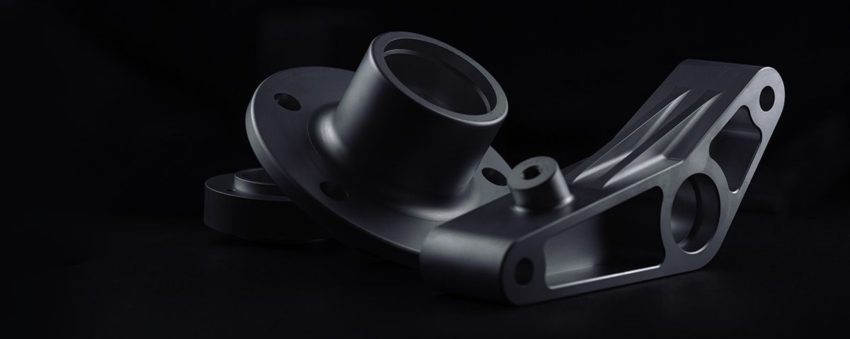 Machined aluminum part with milled webbing and bored hardware mounting points, photographed in low-key lighting.